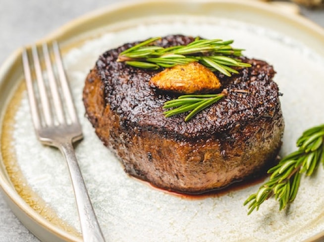 filet mignon on plate with rosemary spring and fork